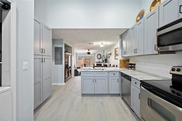 kitchen featuring a peninsula, appliances with stainless steel finishes, and gray cabinets