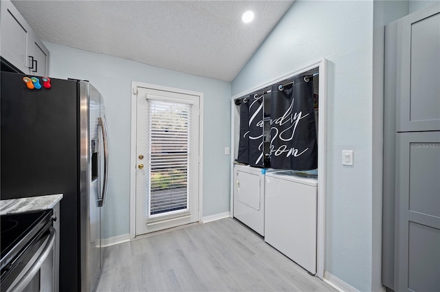 interior space with light wood-type flooring, baseboards, a textured ceiling, and washing machine and clothes dryer