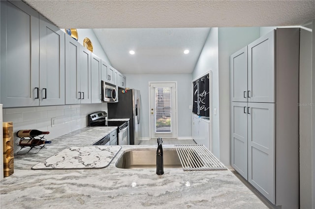 kitchen with stainless steel appliances, lofted ceiling, light stone countertops, and tasteful backsplash