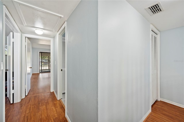 corridor featuring visible vents, baseboards, and wood finished floors