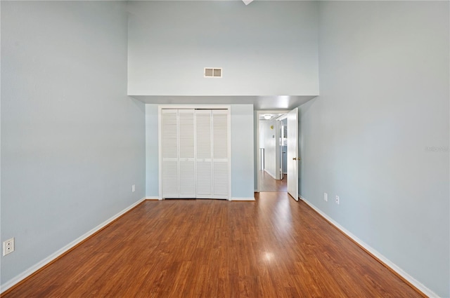 unfurnished bedroom with a closet, visible vents, baseboards, and wood finished floors