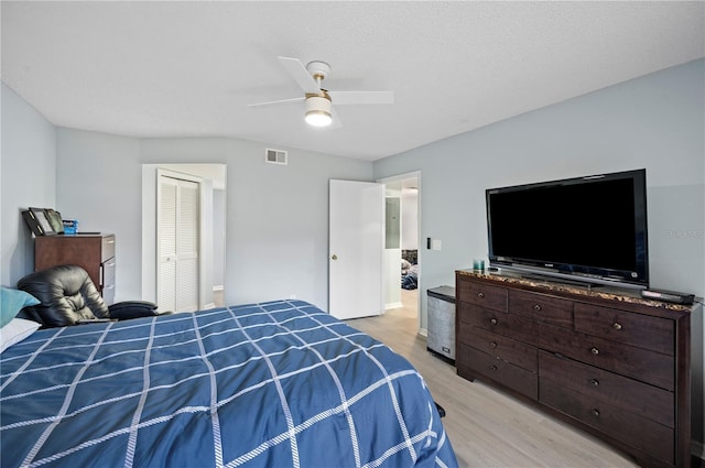 bedroom featuring a closet, visible vents, ceiling fan, a textured ceiling, and light wood-type flooring