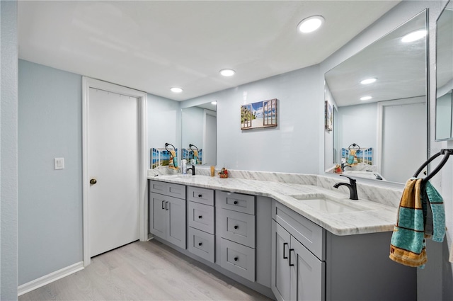 full bathroom with recessed lighting, wood finished floors, a sink, and double vanity