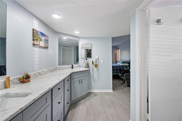 bathroom featuring wood finished floors, double vanity, a sink, and ensuite bathroom