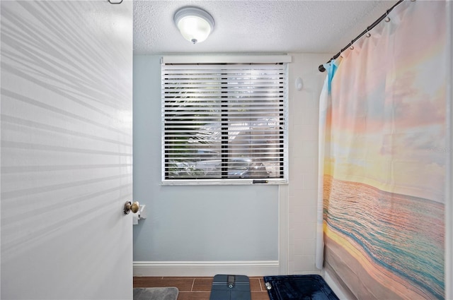 full bathroom featuring plenty of natural light, a textured ceiling, and a shower with shower curtain