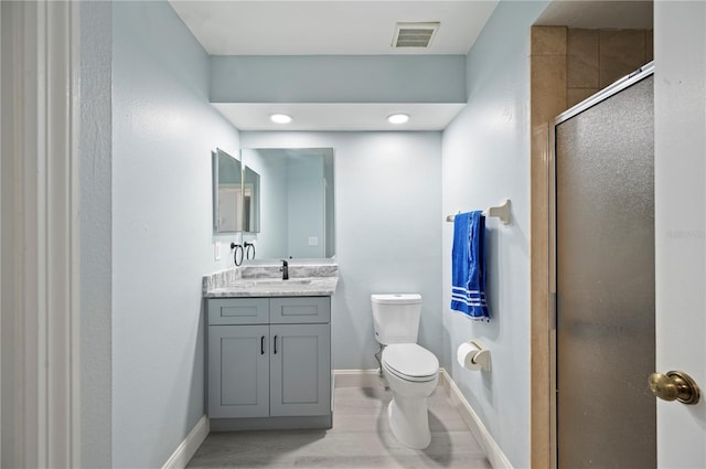 bathroom featuring visible vents, toilet, a shower stall, vanity, and baseboards