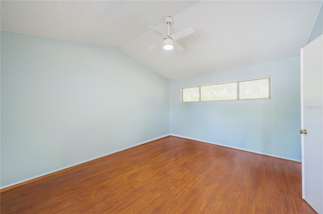 spare room featuring lofted ceiling, ceiling fan, wood finished floors, and baseboards