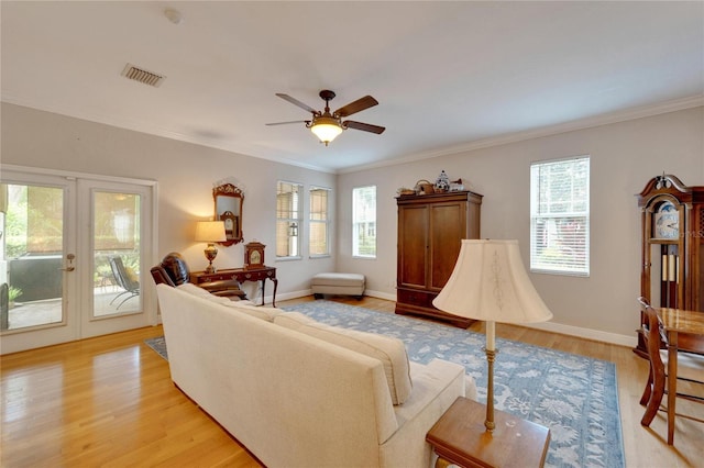 living area featuring ornamental molding, light wood-style flooring, plenty of natural light, and visible vents