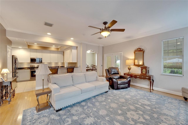 living area with visible vents, crown molding, light wood finished floors, and baseboards