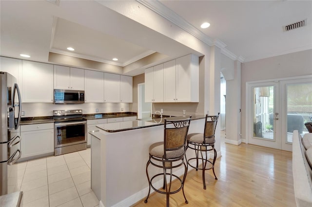 kitchen featuring visible vents, dark countertops, appliances with stainless steel finishes, a peninsula, and crown molding