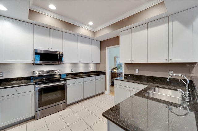 kitchen with light tile patterned floors, appliances with stainless steel finishes, a tray ceiling, crown molding, and a sink