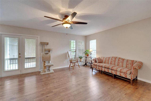 living area featuring ceiling fan, baseboards, and wood finished floors