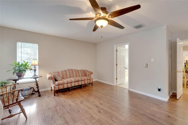 living area featuring light wood finished floors, ceiling fan, visible vents, and baseboards