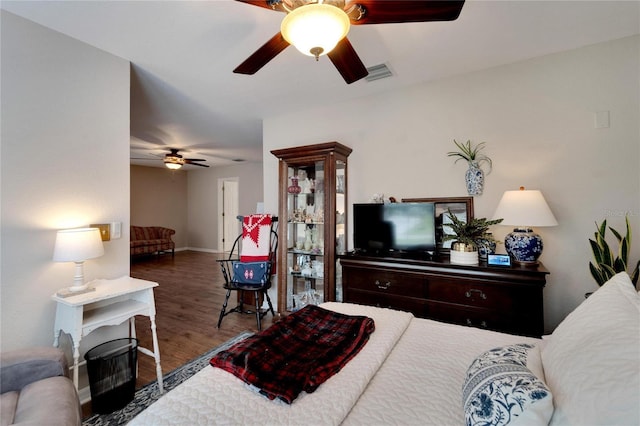 bedroom with baseboards, wood finished floors, visible vents, and a ceiling fan