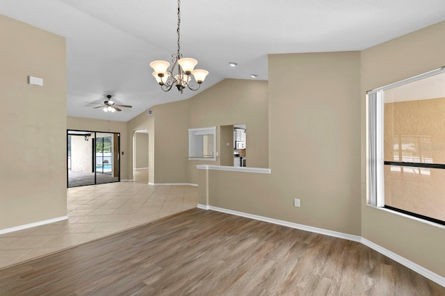 spare room with ceiling fan with notable chandelier, vaulted ceiling, and wood-type flooring