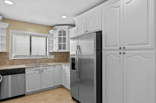 kitchen featuring sink, backsplash, appliances with stainless steel finishes, and light stone counters