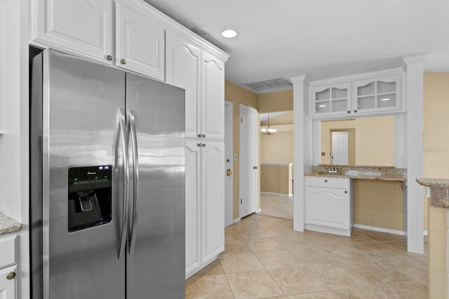 kitchen featuring light stone counters, stainless steel fridge with ice dispenser, light tile patterned floors, and white cabinetry