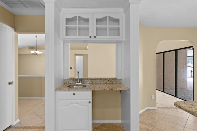 kitchen featuring sink, white cabinets, hanging light fixtures, and light tile patterned floors