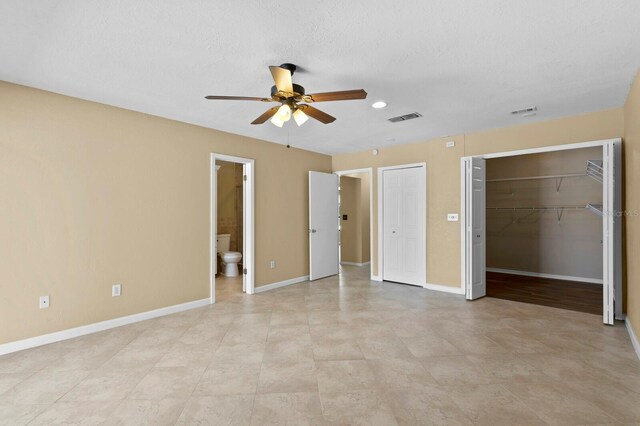 unfurnished bedroom featuring ceiling fan, a closet, light tile patterned floors, connected bathroom, and a textured ceiling