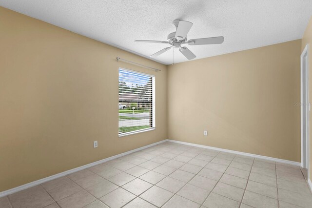 spare room with ceiling fan, light tile patterned floors, and a textured ceiling