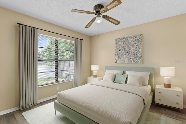 bedroom with multiple windows, a textured ceiling, hardwood / wood-style flooring, and ceiling fan