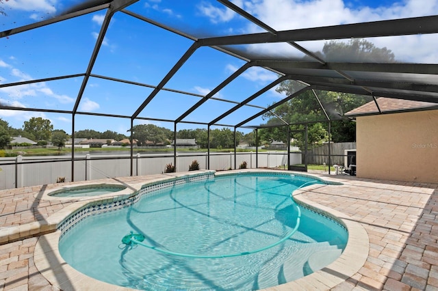 view of swimming pool with an in ground hot tub, glass enclosure, and a patio area