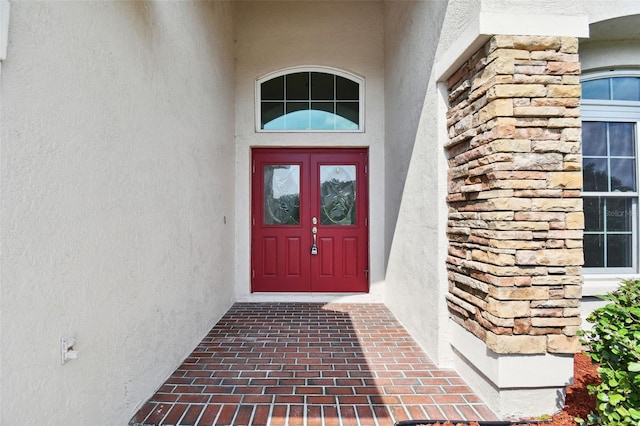 view of exterior entry with stone siding and stucco siding