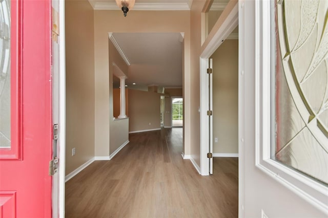 entryway with baseboards, ornate columns, light wood finished floors, and crown molding