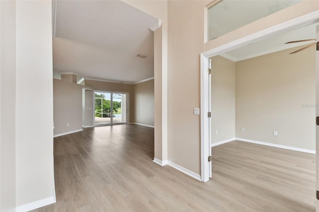 spare room with ceiling fan, ornamental molding, light wood-type flooring, and baseboards