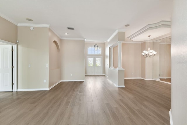 empty room featuring decorative columns, baseboards, visible vents, ornamental molding, and wood finished floors