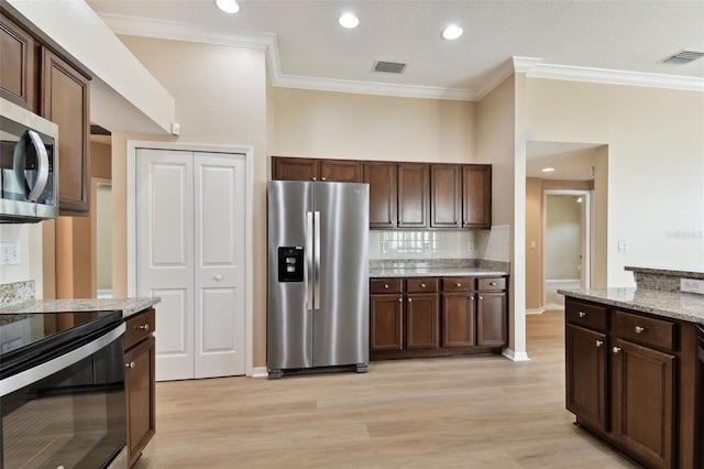 kitchen featuring light stone counters, visible vents, dark brown cabinets, appliances with stainless steel finishes, and light wood finished floors