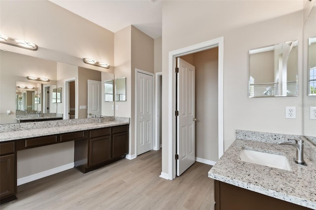 bathroom with a closet, vanity, baseboards, and wood finished floors