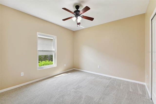 carpeted empty room with ceiling fan and baseboards