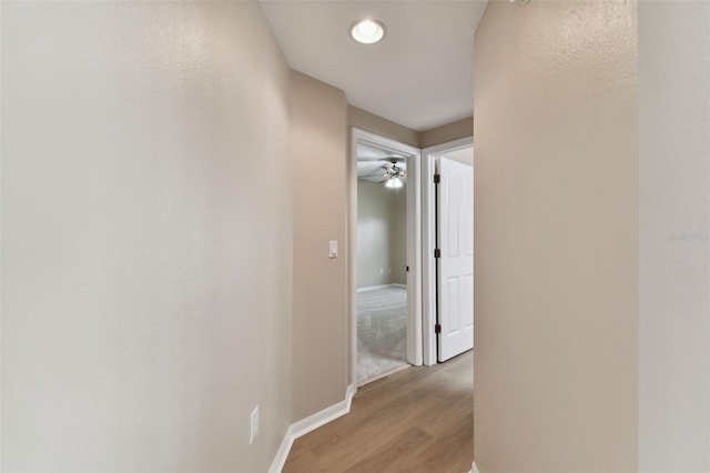 hall featuring light wood-style flooring and baseboards