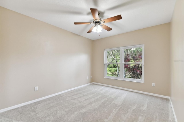 spare room featuring light carpet, ceiling fan, and baseboards