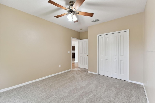 unfurnished bedroom with baseboards, visible vents, a closet, and light colored carpet