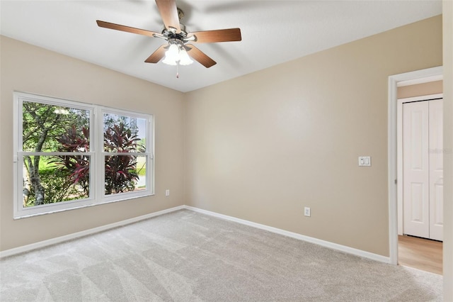 unfurnished room featuring light carpet, baseboards, and a ceiling fan