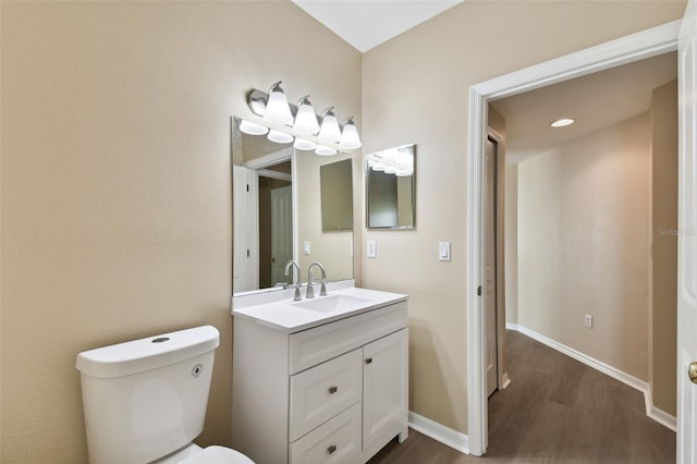 half bathroom featuring vanity, wood finished floors, toilet, and baseboards