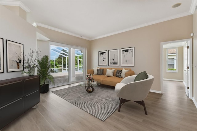 living area with light wood-type flooring, crown molding, and baseboards