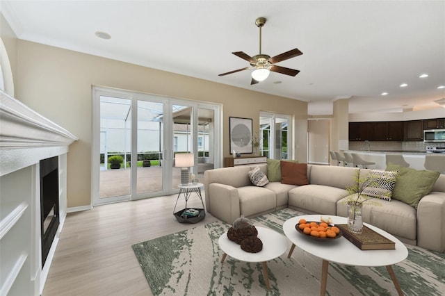 living area with ceiling fan, light wood-type flooring, baseboards, and recessed lighting