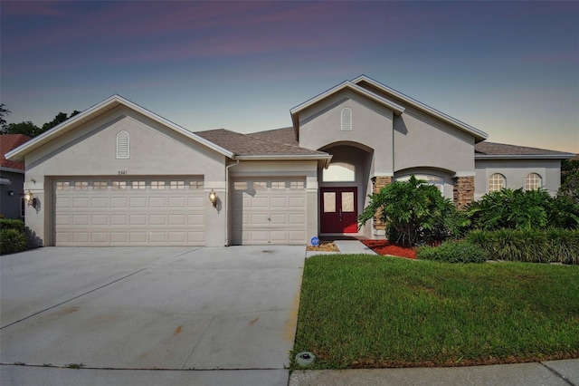 view of front of home with a garage, a front yard, concrete driveway, and stucco siding