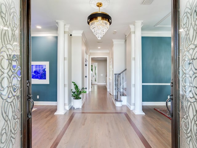 entryway featuring ornamental molding, ornate columns, and wood-type flooring