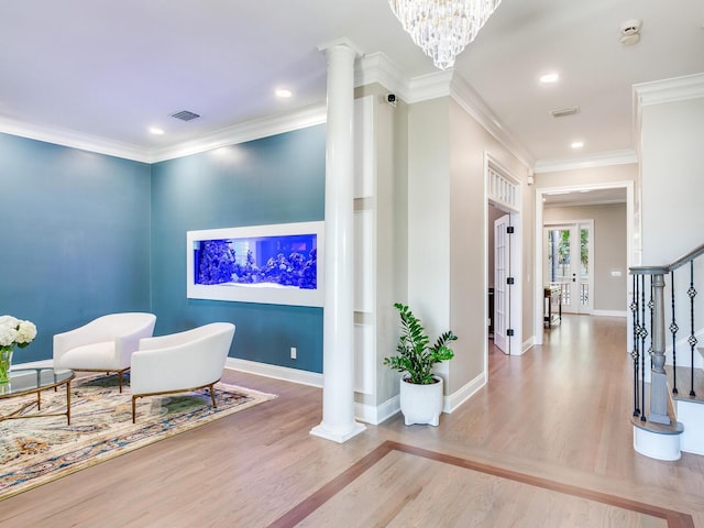 interior space featuring an inviting chandelier, ornate columns, crown molding, and hardwood / wood-style flooring