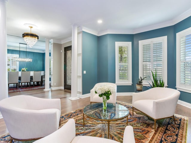 living room featuring decorative columns, wood-type flooring, and a chandelier