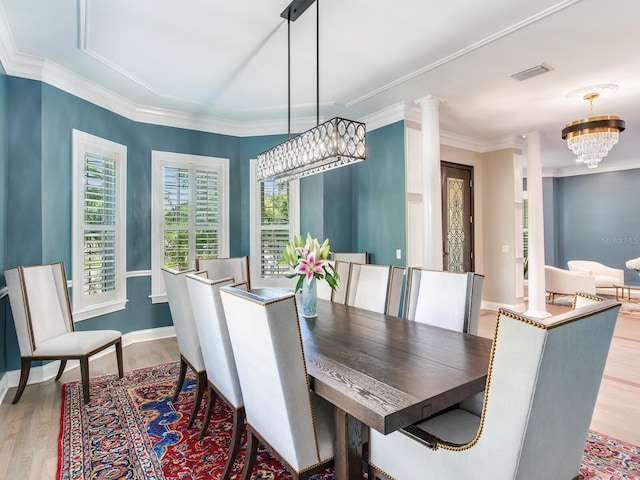 dining space with light hardwood / wood-style flooring, a chandelier, ornate columns, and ornamental molding