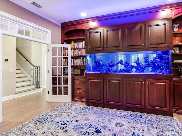 bar featuring light wood-type flooring and ornamental molding