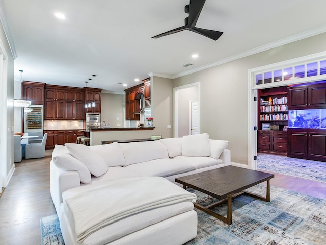 living room with light hardwood / wood-style flooring, crown molding, and ceiling fan