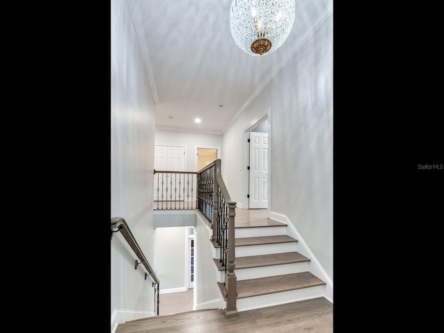 stairs featuring an inviting chandelier, ornamental molding, and hardwood / wood-style flooring