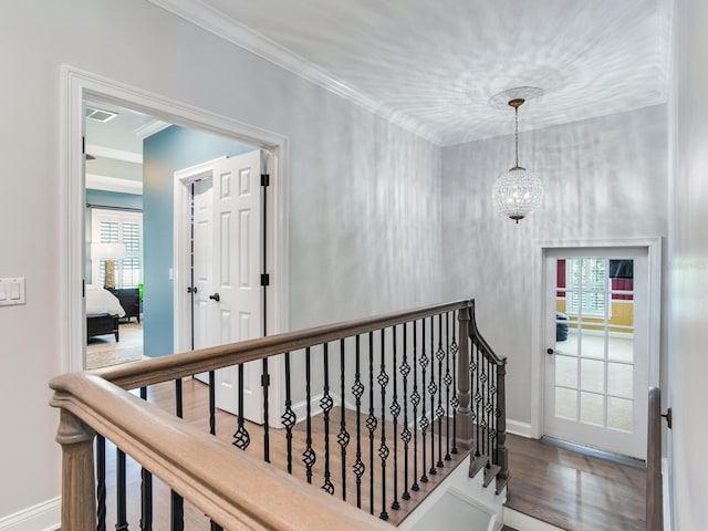 corridor featuring crown molding, hardwood / wood-style flooring, and an inviting chandelier