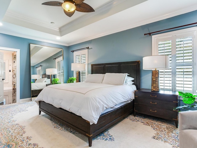 bedroom with ceiling fan, a raised ceiling, ensuite bathroom, and ornamental molding